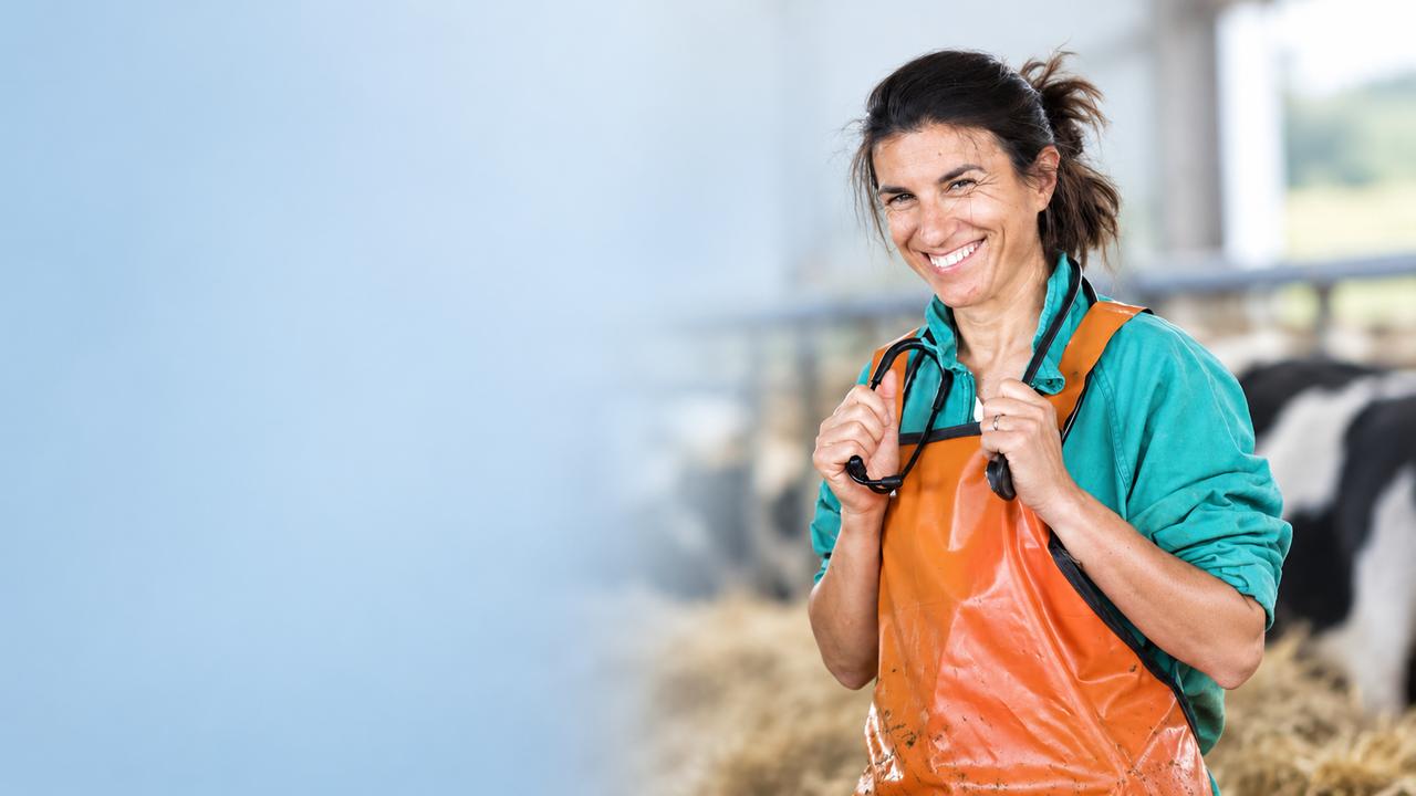 Emanuela Sorgia in stalla, sorridente, con il grembiule da lavoro